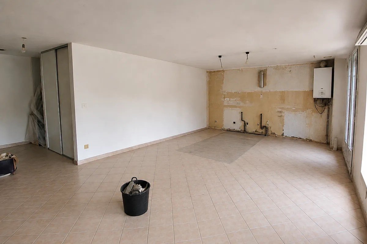 Pièce au carrelage d'origine, mur décapé et chaudière apparente avant travaux